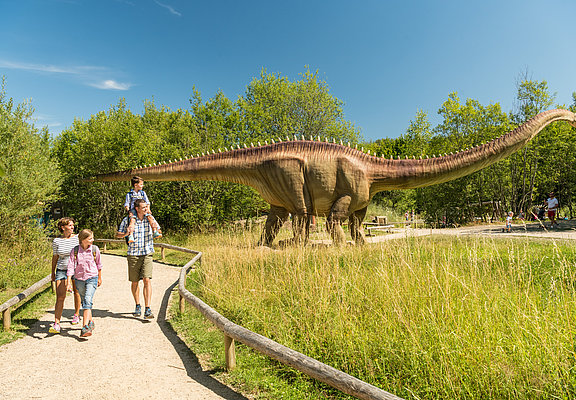 Das Bild zeigt eine Familie im Dinopark Teufelsschlucht.